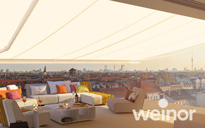 Dachterrasse mit ausgefahrener Markise, Loungegarnitur, mit Blick über die Dächer einer Stadt